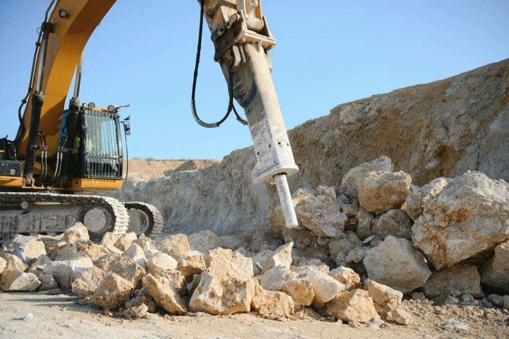 Excavator with hydraulic hammer on road construction works